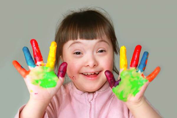 kleines Mädchen hat ihre Hände mit Handmalfarben bemalt und lächelt in die Kamera